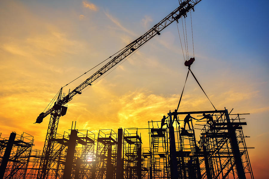 Silhouette of engineer and safety officer looking construction worker pouring a concrete column on scaffolding in construction  site Photograph by Jung Getty