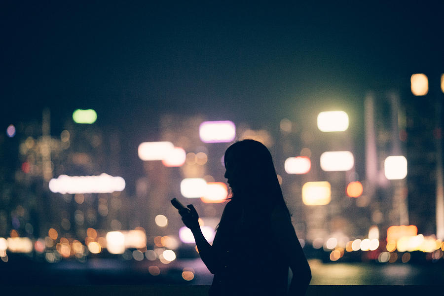 Silhouette of office lady using smartphone in city Photograph by D3sign