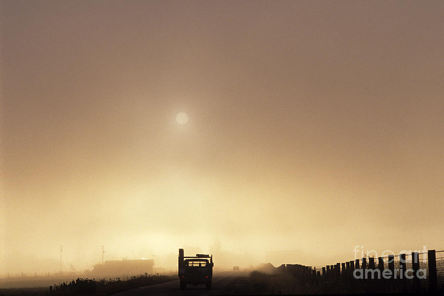 Silhouetted truck along rural highway at sunrise in fog  Photograph by Jim Corwin