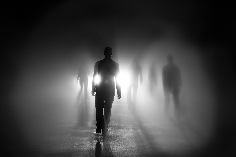 Silhouettes of people walking into light Photograph by AMR Image