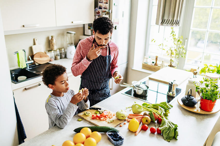 Single Dad Snacking With His Son While Preparing Lunch Photograph by Tom Werner