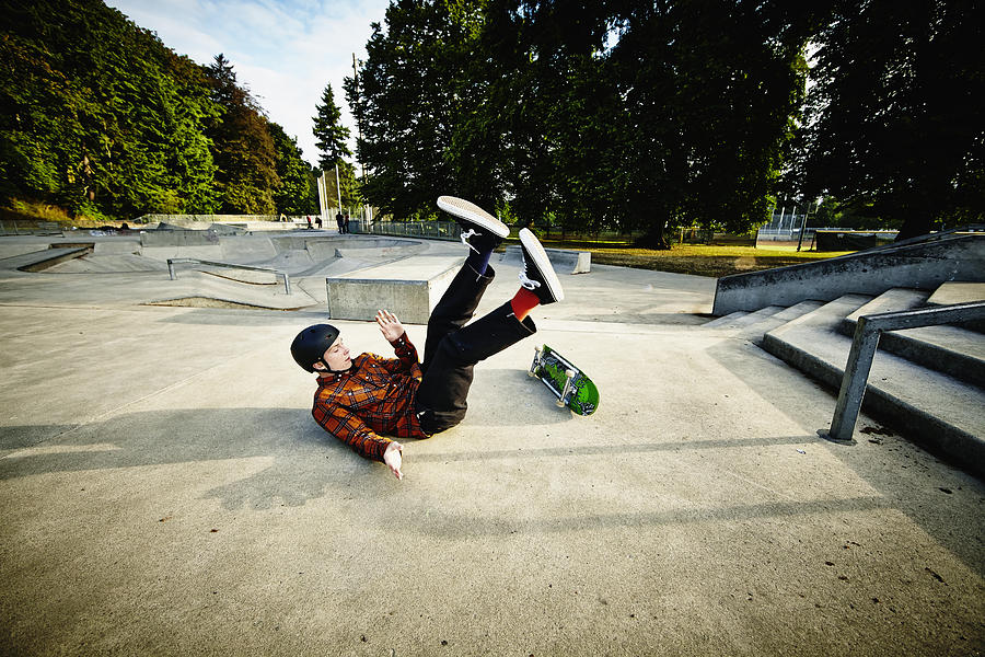 Skateboarder falling off of railing in skate park Photograph by Thomas Barwick