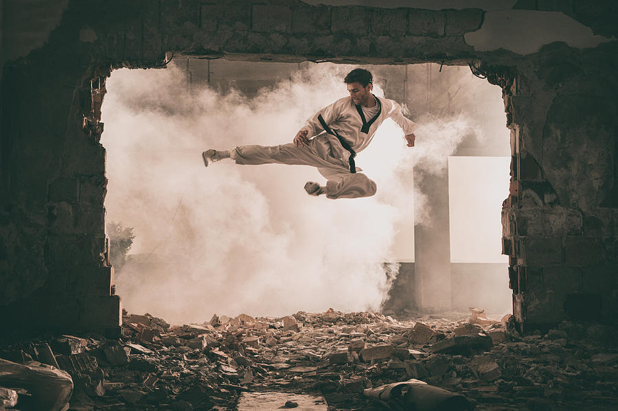Skilful black belt martial artist performing fly kick. Photograph by Skynesher