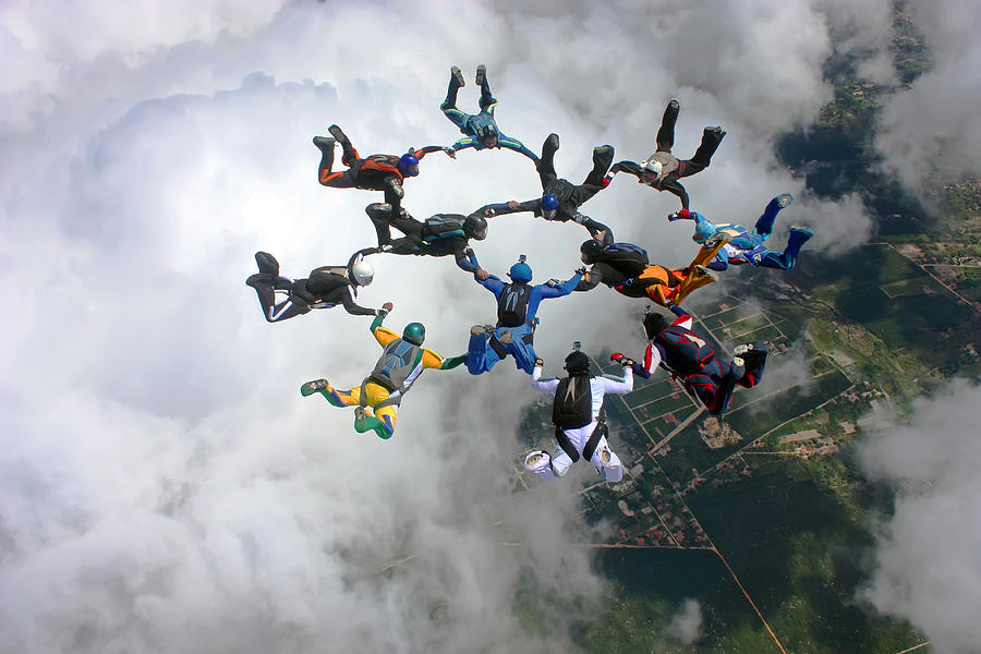 Skydivers make a formation above the clouds Photograph by Graiki