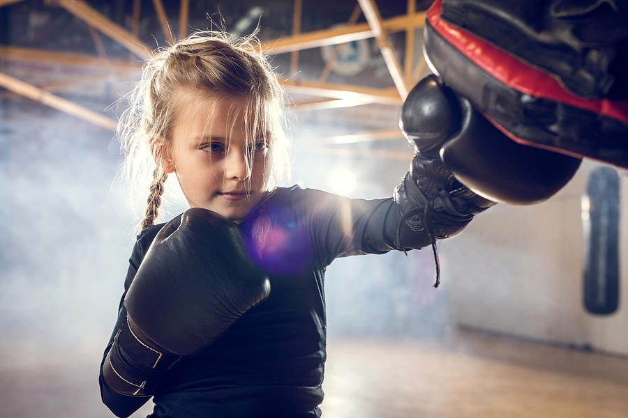Small boxer exercising punches on a sports training in a gym. Photograph by Skynesher