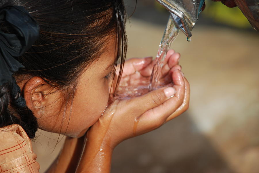 Small dark haired child drinking water using her hands Photograph by Vardhan