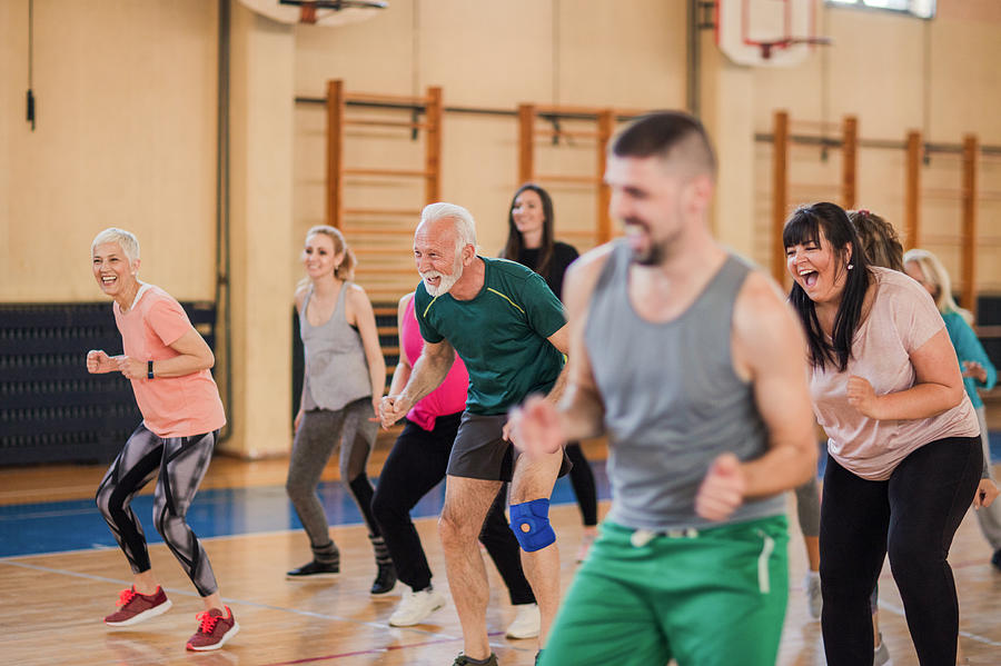 Smiling and happy group of people dancing at gym Photograph by Anchiy