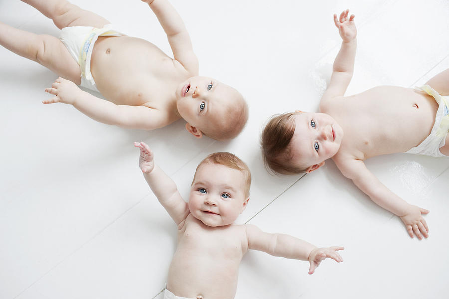Smiling babies laying on floor Photograph by Tom Merton