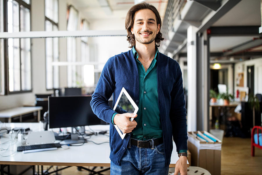 Smiling businessman standing with digital tablet Photograph by Luis Alvarez