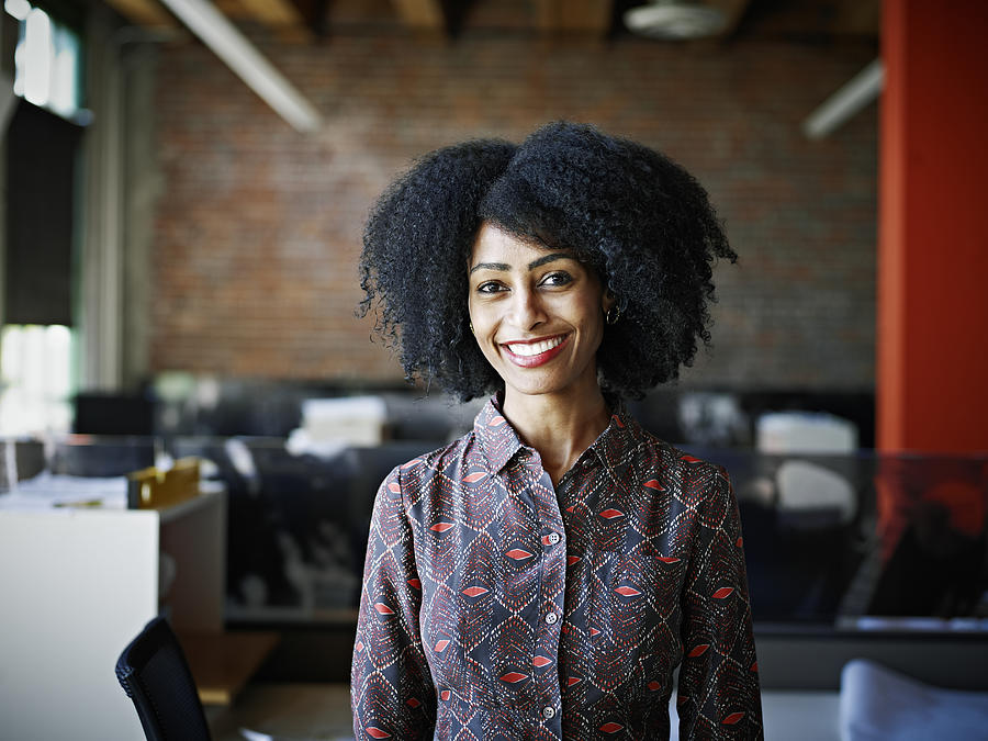 Smiling businesswoman standing in office Photograph by Thomas Barwick