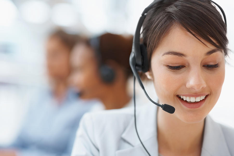 Smiling call center employee during a telephone conversation Photograph by Jacob Wackerhausen