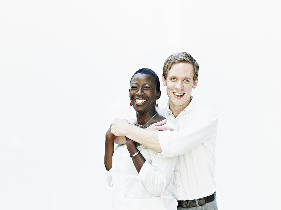 Smiling couple embracing against white background Photograph by Thomas Barwick