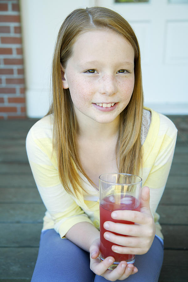 Smiling girl (10-11) with drink outdoors Photograph by Compassionate Eye Foundation