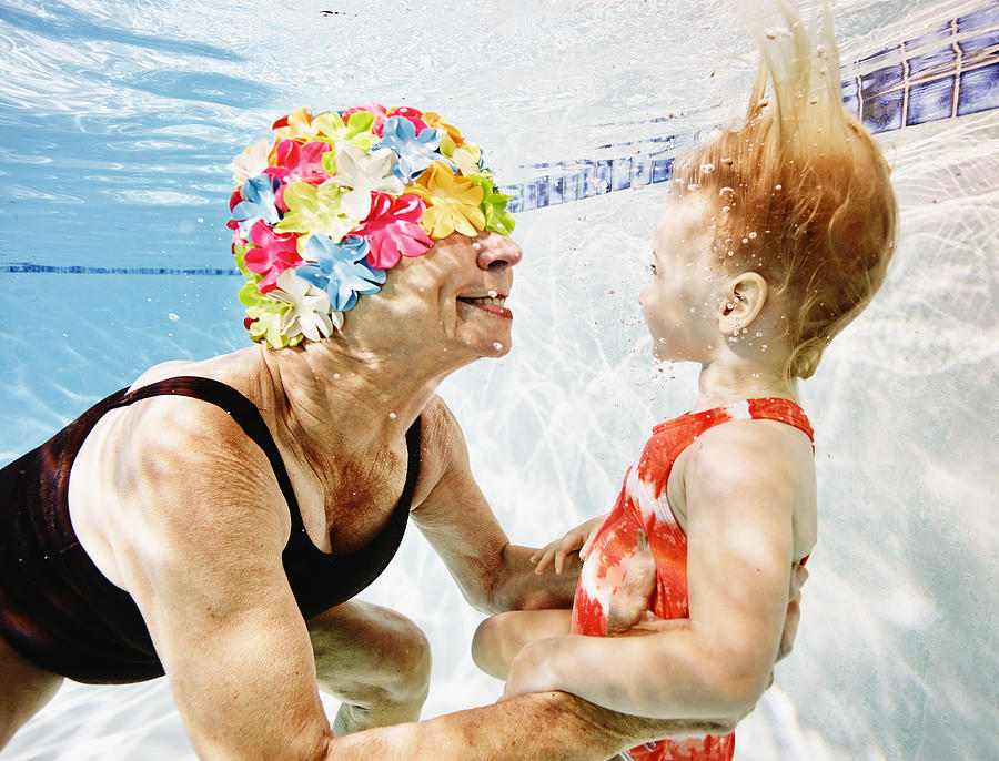 Smiling grandmother and granddaughter underwater Photograph by Thomas Barwick