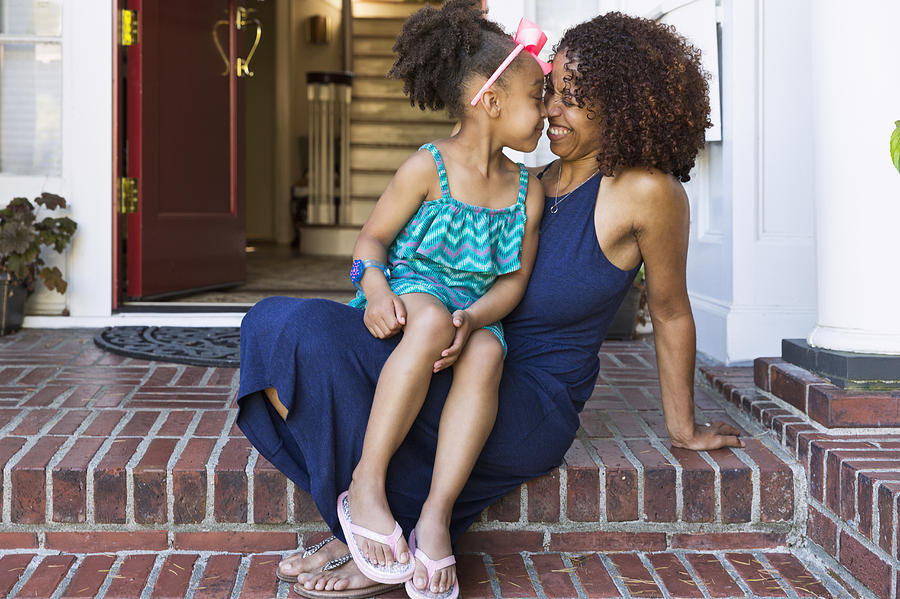 Smiling mixed race mother and daughter rubbing noses on front stoop Photograph by Don Mason