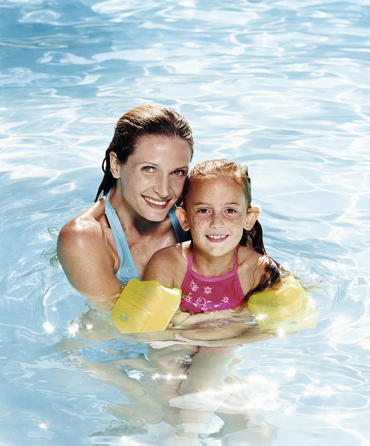 Smiling Mother Holding Her Daughter in a Swimming Pool Photograph by Digital Vision.