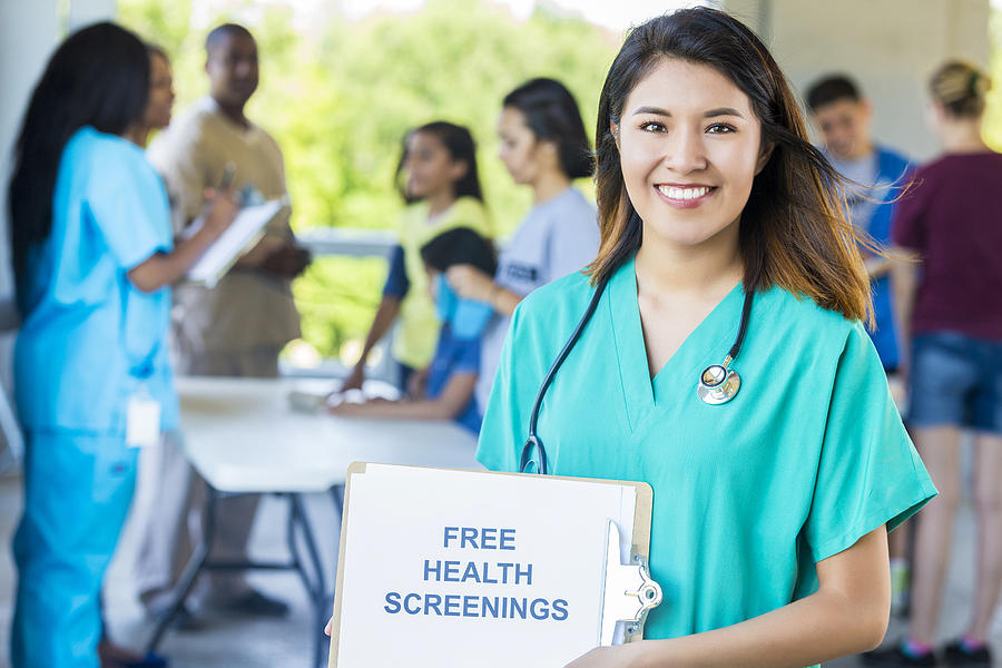 Smiling nurse holding up a Free Health Screenings sign Photograph by Steve Debenport