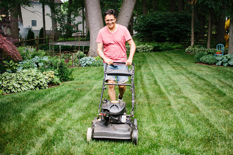 Smiling older man mowing the lawn in a backyard Photograph by Stephanie Noritz