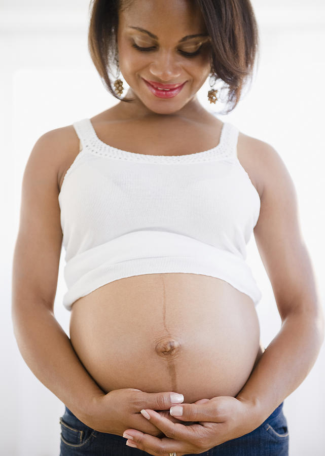 Smiling pregnant Black woman holding stomach Photograph by JGI/Jamie Grill