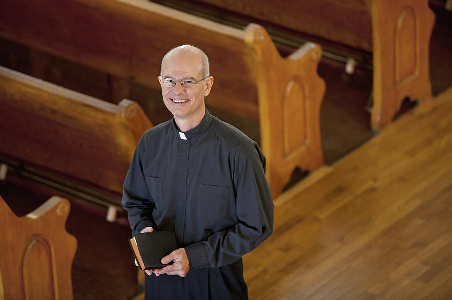 Smiling priest standing in church Photograph by Monashee Frantz