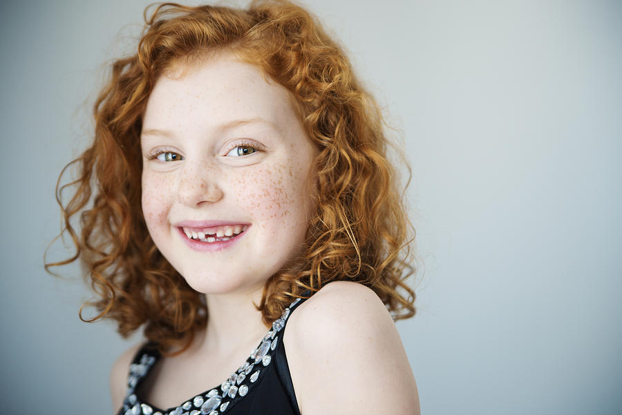 Smiling redhead little girl with freckles and missing tooth. Photograph by Martinedoucet