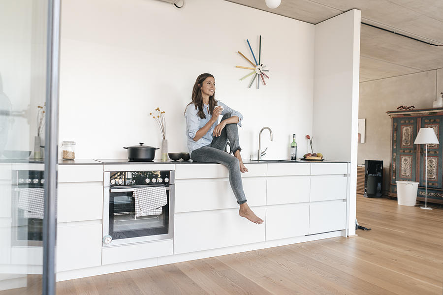 Smiling woman relaxing in kitchen at home Photograph by Westend61