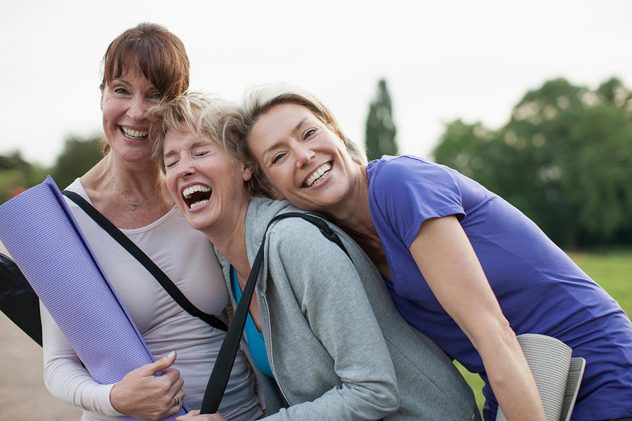 Smiling women holding yoga mats Photograph by Tom Merton
