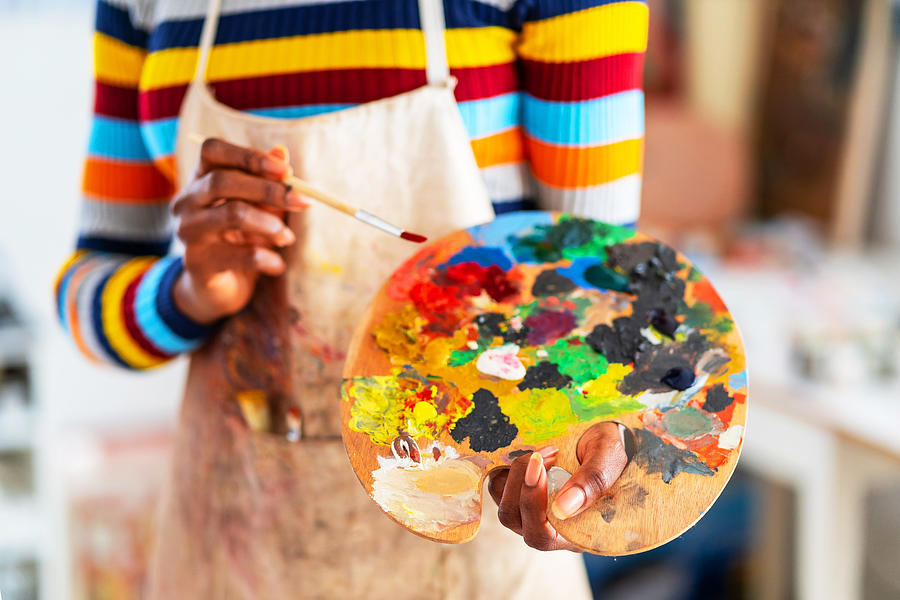 Smiling young afro woman holding color palette and paintbrush Photograph by Valentinrussanov