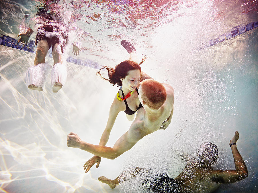 Smiling young couple embracing underwater Photograph by Thomas Barwick