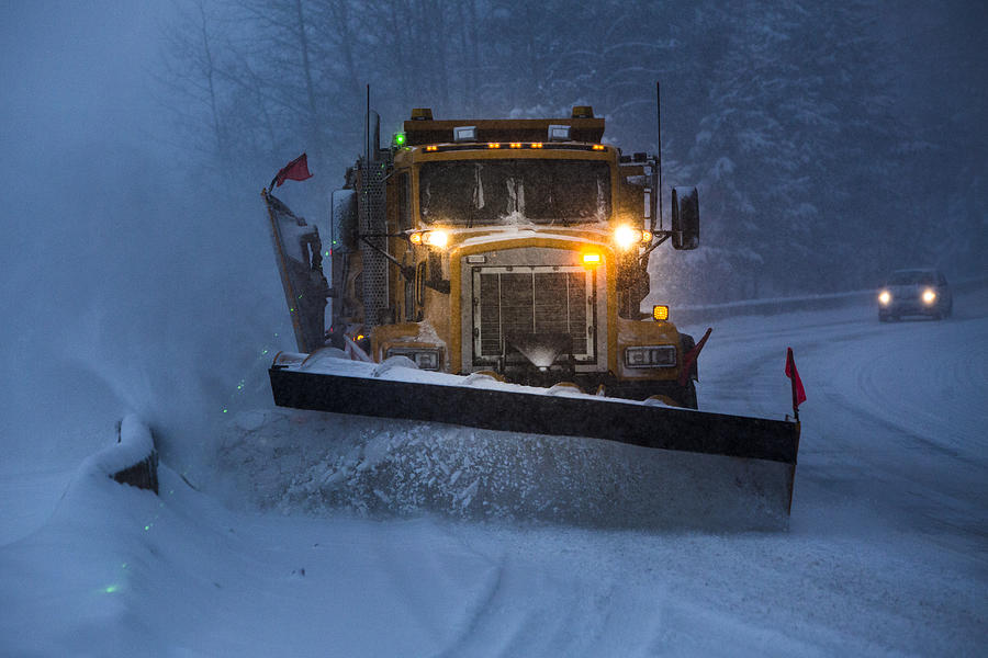 Snowplow plowing the highway during snow storm. Photograph by VisualCommunications