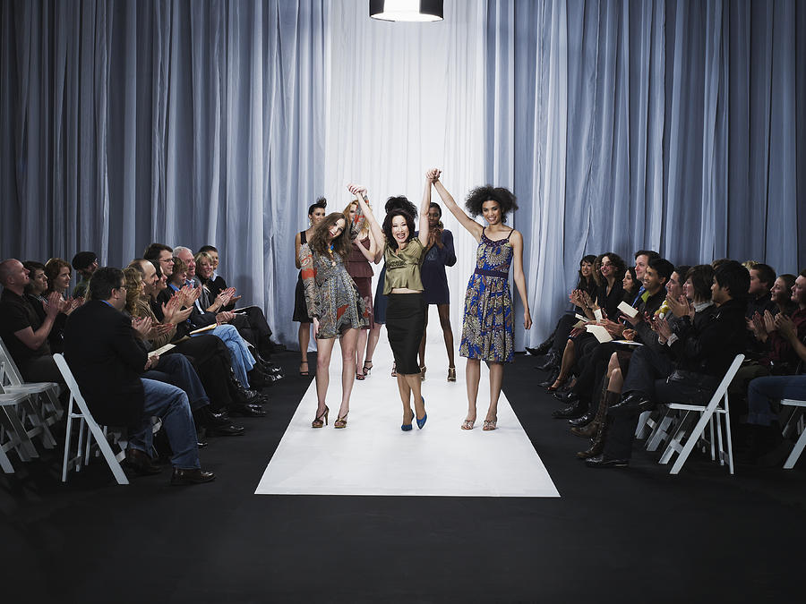 Spectators applauding for designer and female models on catwalk Photograph by Thomas Barwick