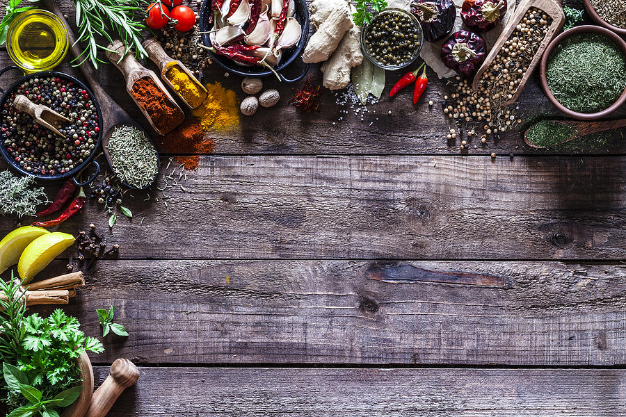 Spices and herbs border on rustic wood kitchen table Photograph by Fcafotodigital