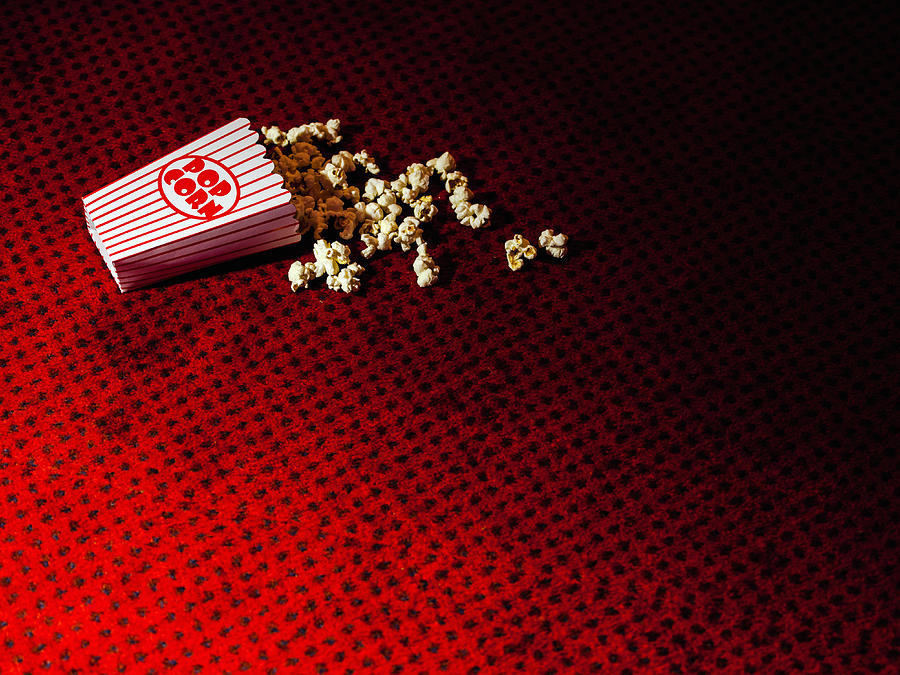 Spilled carton of popcorn on cinema carpet Photograph by Mark Webster