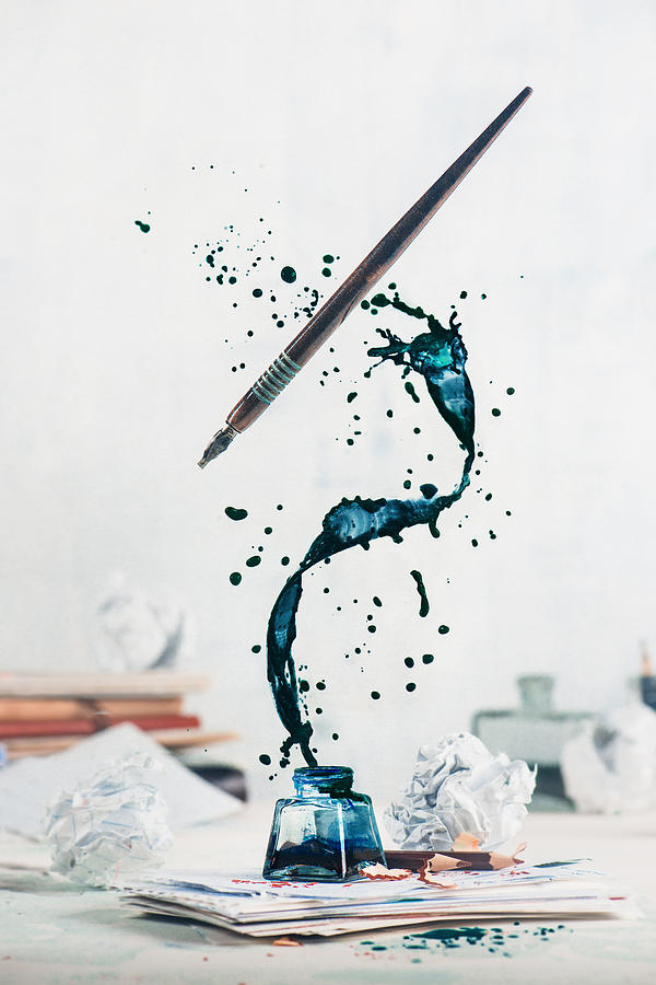 Spilled ink flying above inkwell in a spiraling splash with tiny drops and flying pen on a light background. Still life with writer workplace. Creative writing concept. Photograph by Dina Belenko Photography