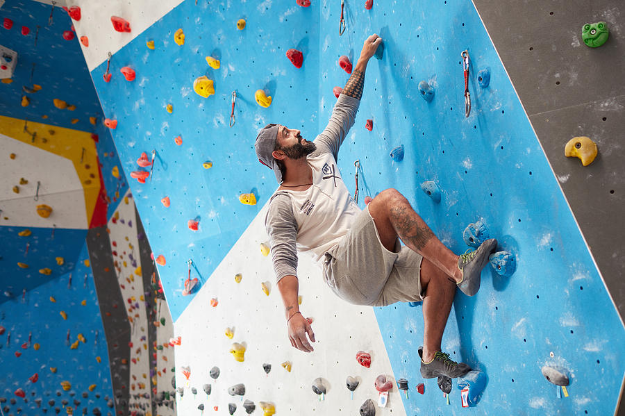 Sporty mature man climbing wall in gym Photograph by Xavierarnau