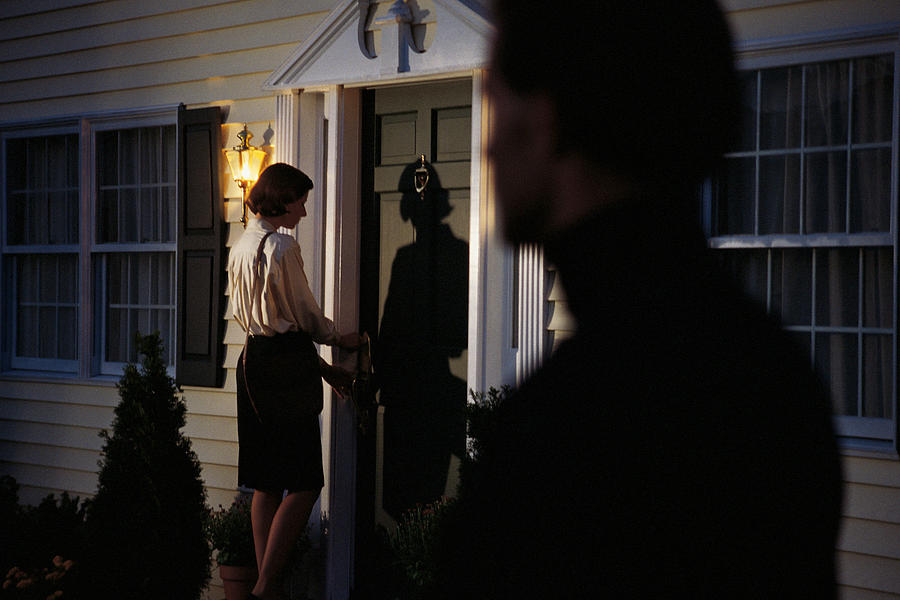 Stalker spying on woman at front door Photograph by Comstock