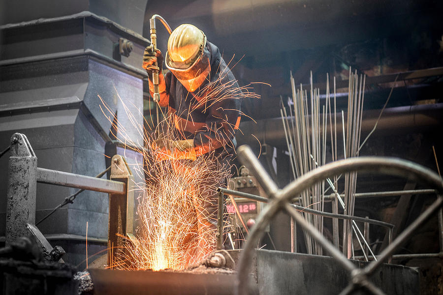 Steel worker amid sparks from molten steel in industrial foundry Photograph by Monty Rakusen