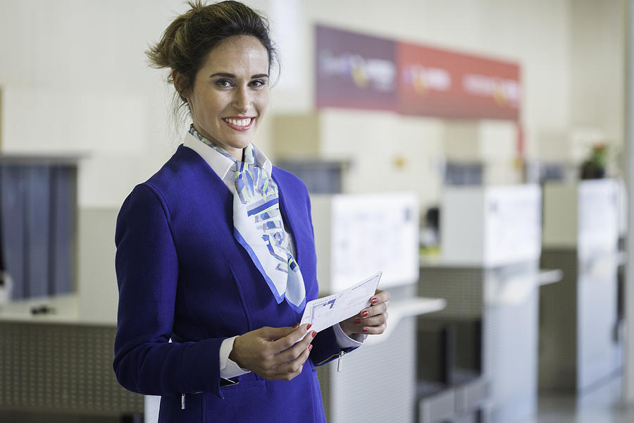 Stewardess looking at camera and holding a boarding pass Photograph by Tempura