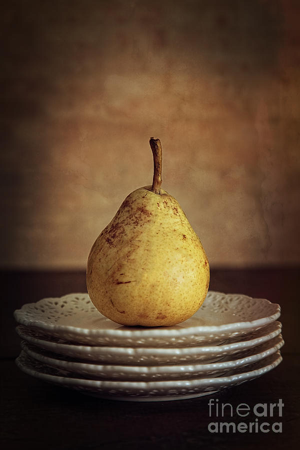 Still life of a pear on plates Photograph by Sandra Cunningham