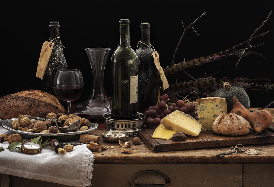 Still life with wine bottles, selection of cheese, bread and nuts on wooden table, studio shot Photograph by Tetra Images
