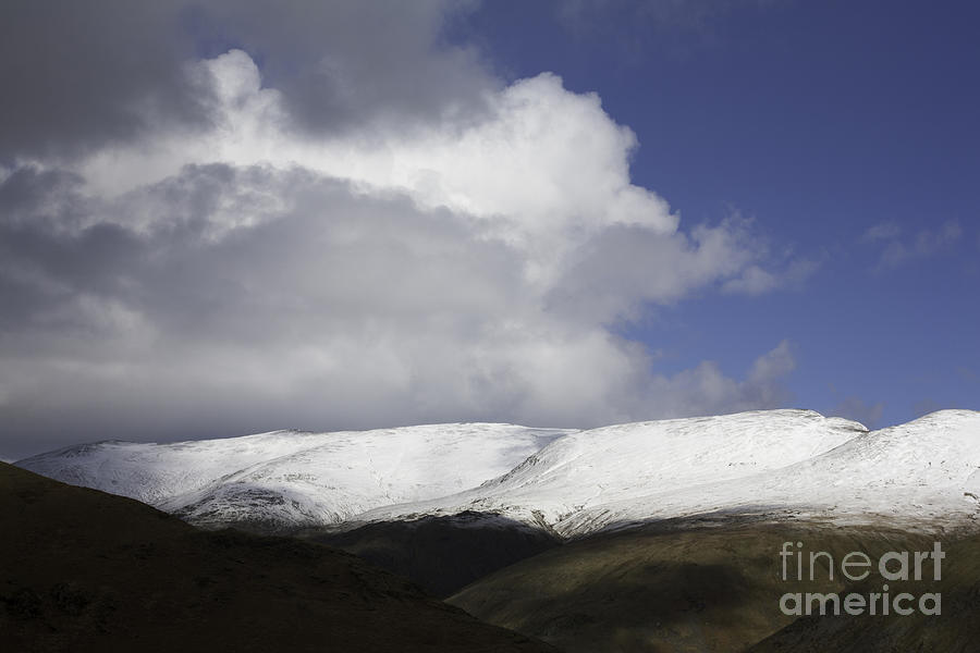 Storm and shower clouds passing over the snow capped summit of Helvellyn from Helm Crag   Photograph by Michael Walters