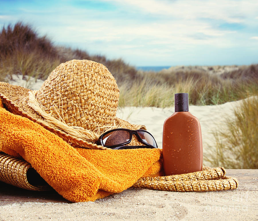 Straw hat with towel and lotion at the beach  Photograph by Sandra Cunningham