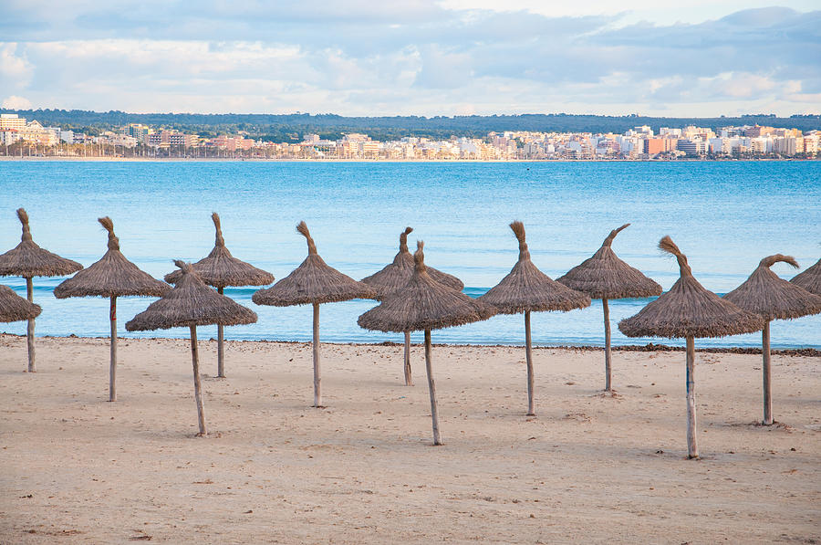 Umbrella Photograph - Straw umbrellas on empty beach by Ingela Christina Rahm