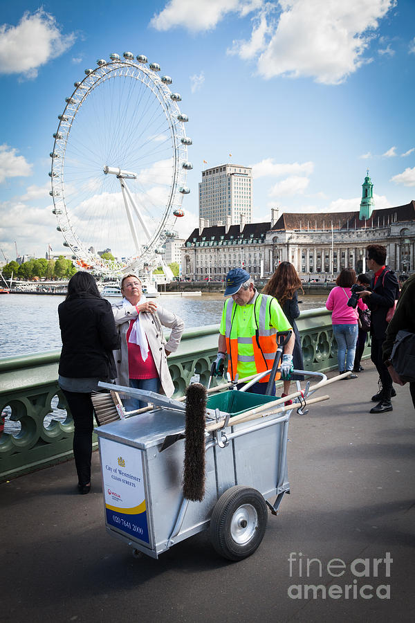 Street cleaner with cart amongst tourists with London Eye. Photograph by Peter Noyce