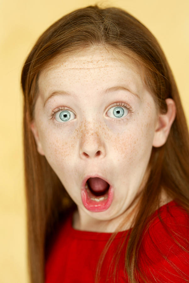 Studio Portrait Of A Young Caucasian Girl In A Red Shirt As She Flashes A Funny Shocked Face Photograph by Photodisc