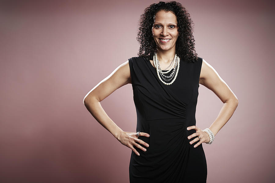 Studio portrait of smiling mature businesswoman with hands on hips Photograph by Jpm