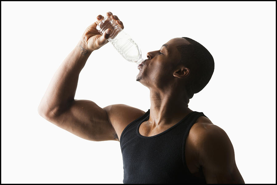 Studio shot of man drinking water from bottle Photograph by Mike Kemp