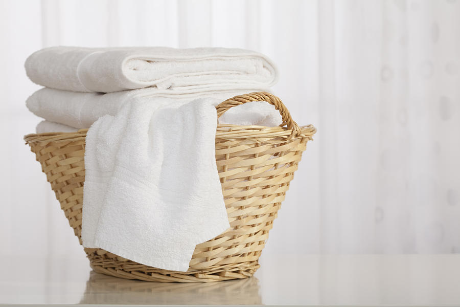 Studio shot of stack of white towels in Wicker Basket Photograph by Vstock LLC