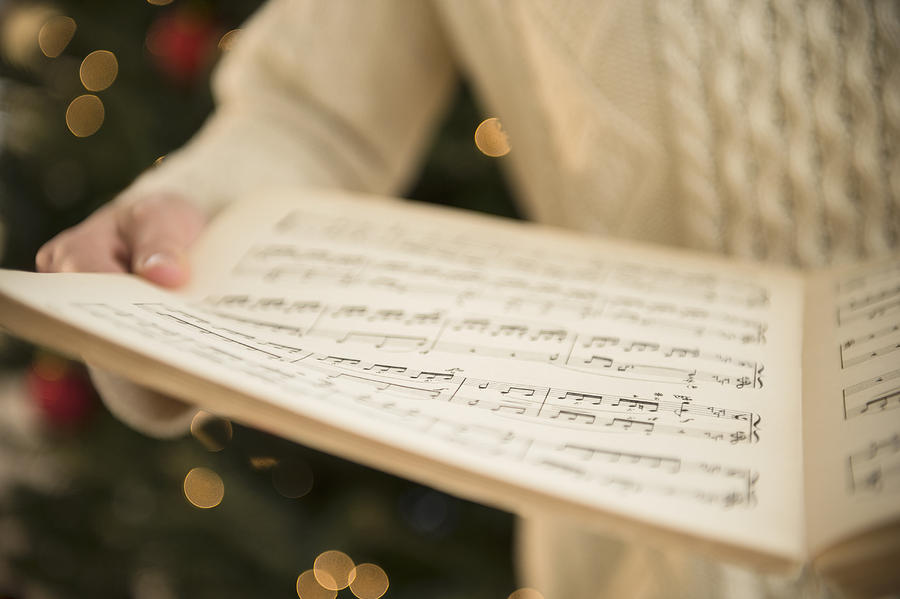 Studio Shot of woman holding sheet music at christmas Photograph by Jamie Grill