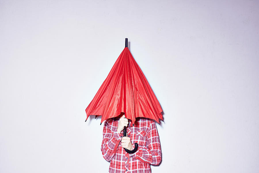 Studio shot of young woman holding red umbrella over her head Photograph by Conny Marshaus